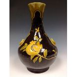 A Bretby globular bottle vase, of Chinese form, decorated in slip with a flower and butterfly,
