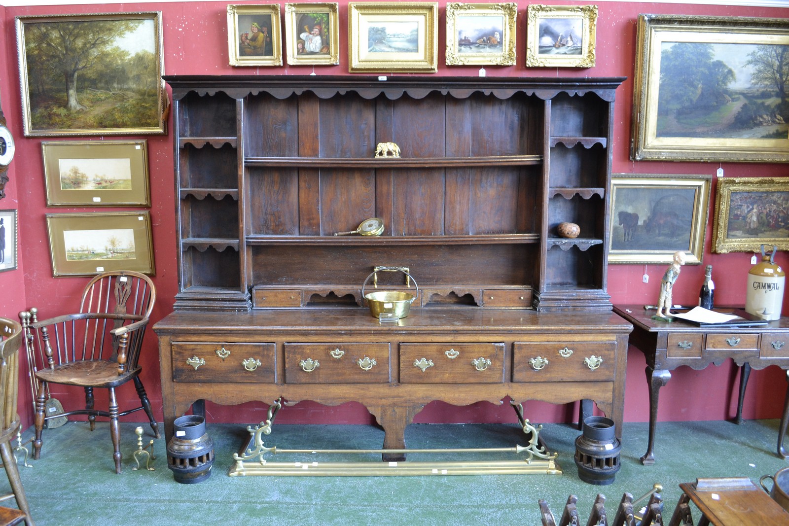 An 18th century oak dresser, moulded cornice, wavy apron above open shelves,