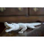 A Japanese ivory okimono, carved as a crocodile, open mouthed and menacing, inlaid eyes, 33cm long,