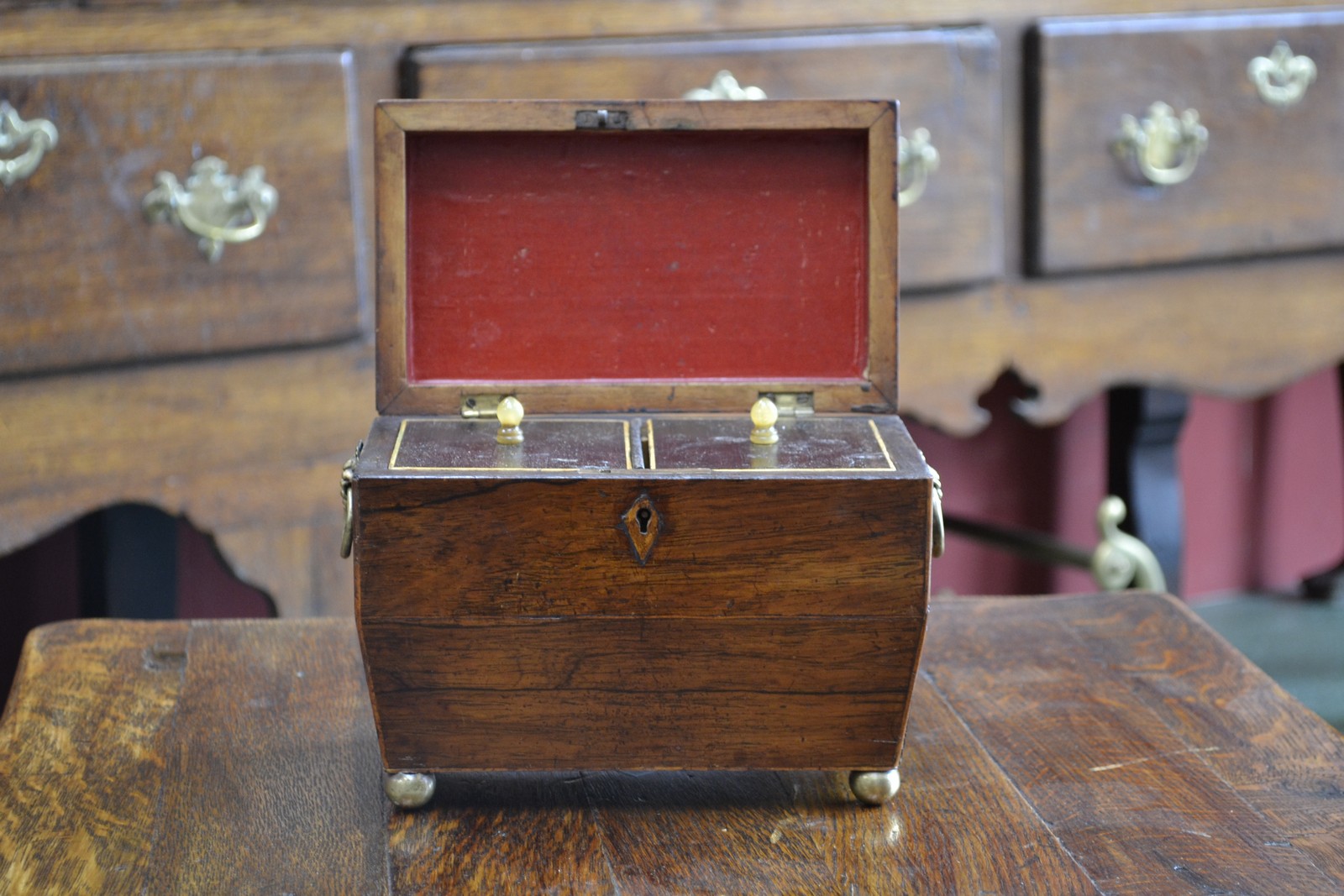 A George IV rosewood sarcophagus tea caddy, hinged cover enclosing a pair of lidded compartments,