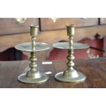 A pair of Dutch brass heemskerk candlesticks, broad drip pan, bobbin column, domed circular bases,