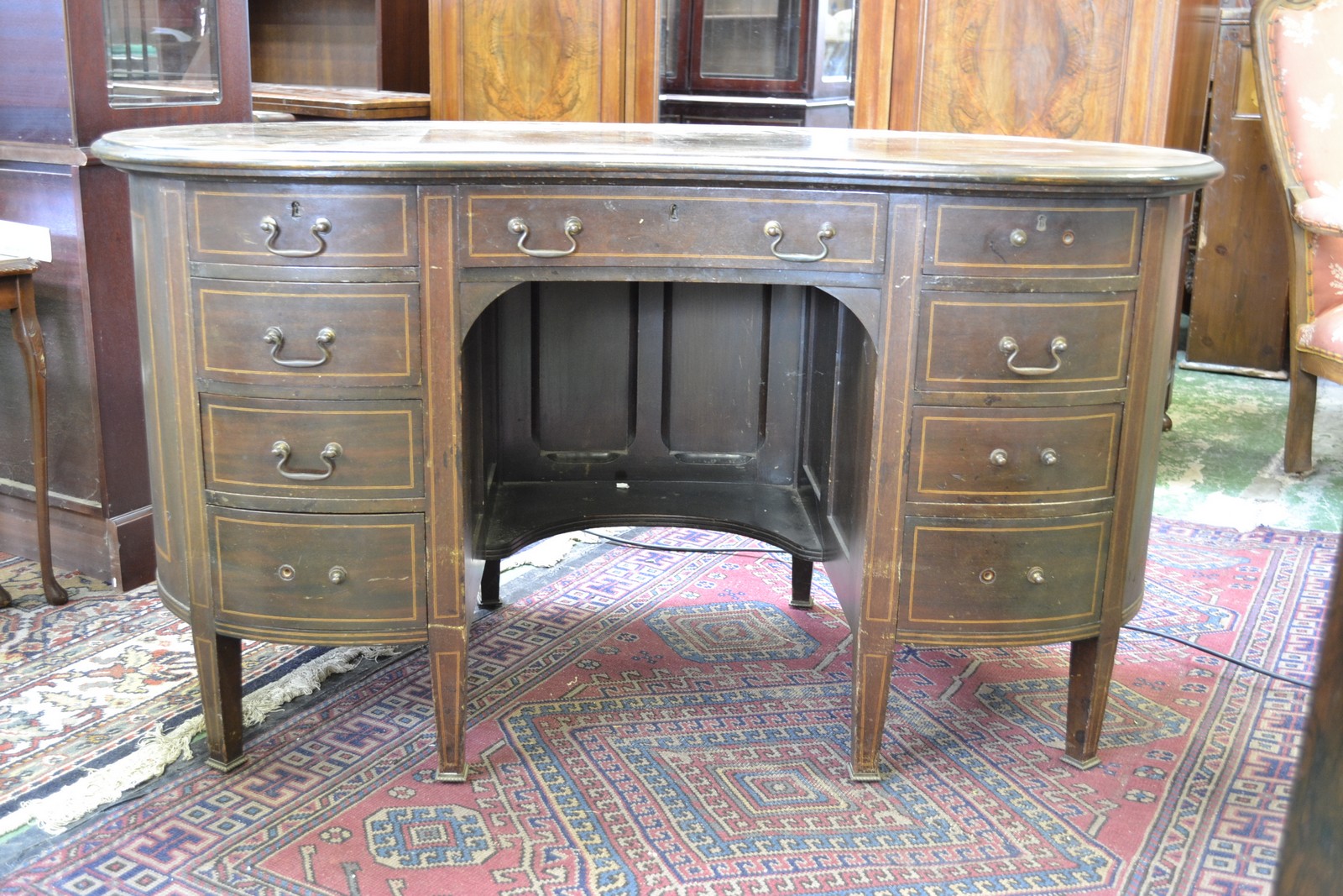 An Edwardian mahogany kidney shaped kneehole desk, moulded top above an arrangement of nine drawers,