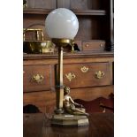 An Art Deco silvered figural table lamp, cast as a female nude seated beside a casket,