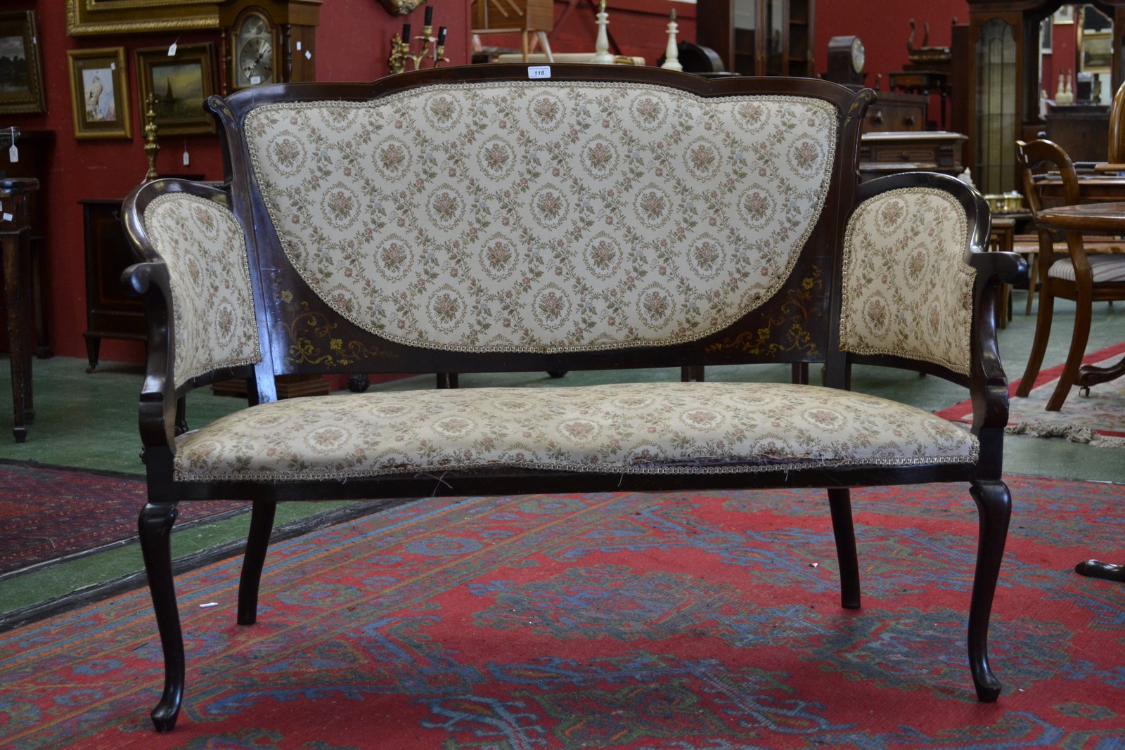 An Edwardian two seat sofa, shaped top rail, padded back, outswept curving arms, padded seat,