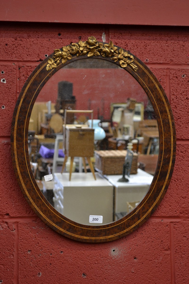 A French gilt metal mounted amboyna oval looking glass, ribbon-tied rose cresting,