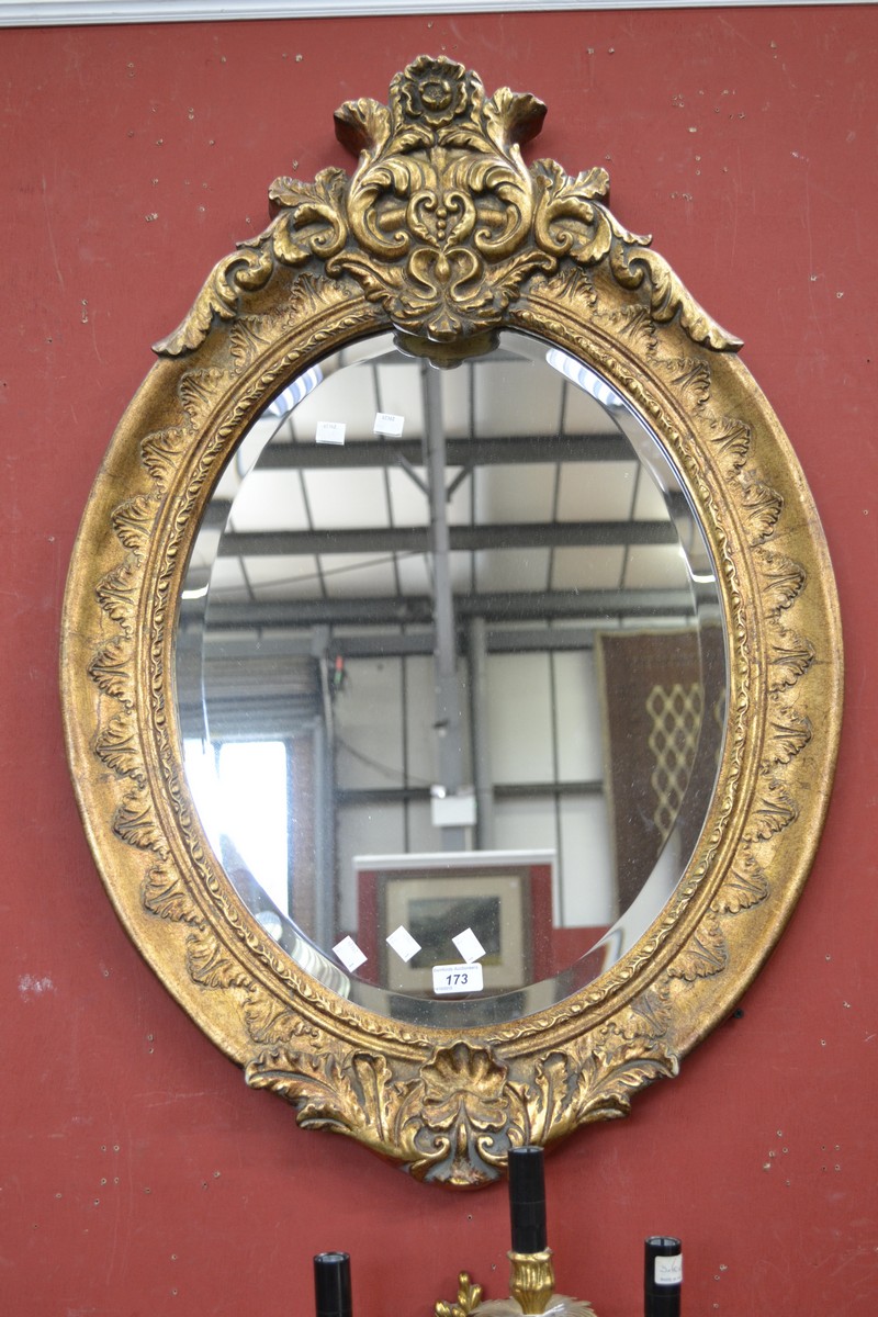 A reproduction gilt framed oval bevel edged mirror