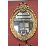 A reproduction gilt framed oval bevel edged mirror