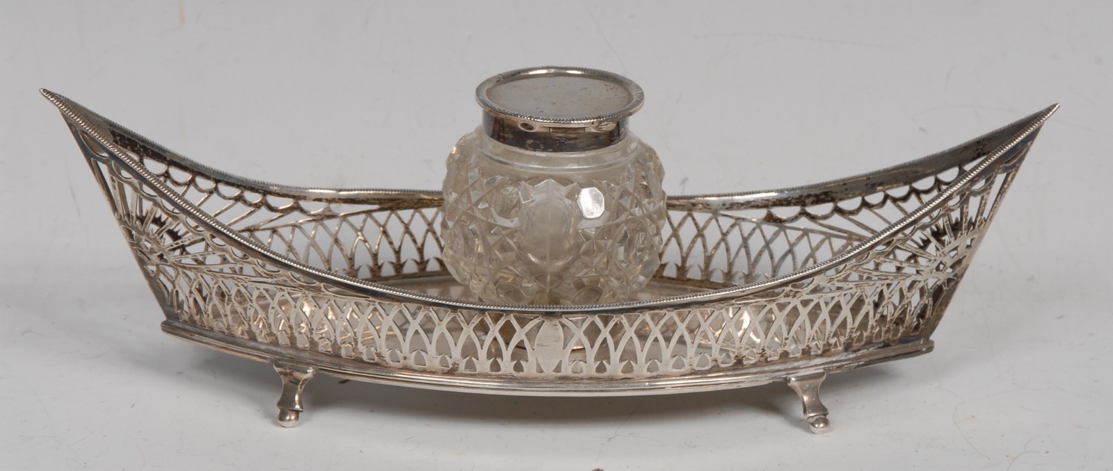 An Edwardian silver navette shaped inkstand, hobnail-cut clear glass well with hinged cover,