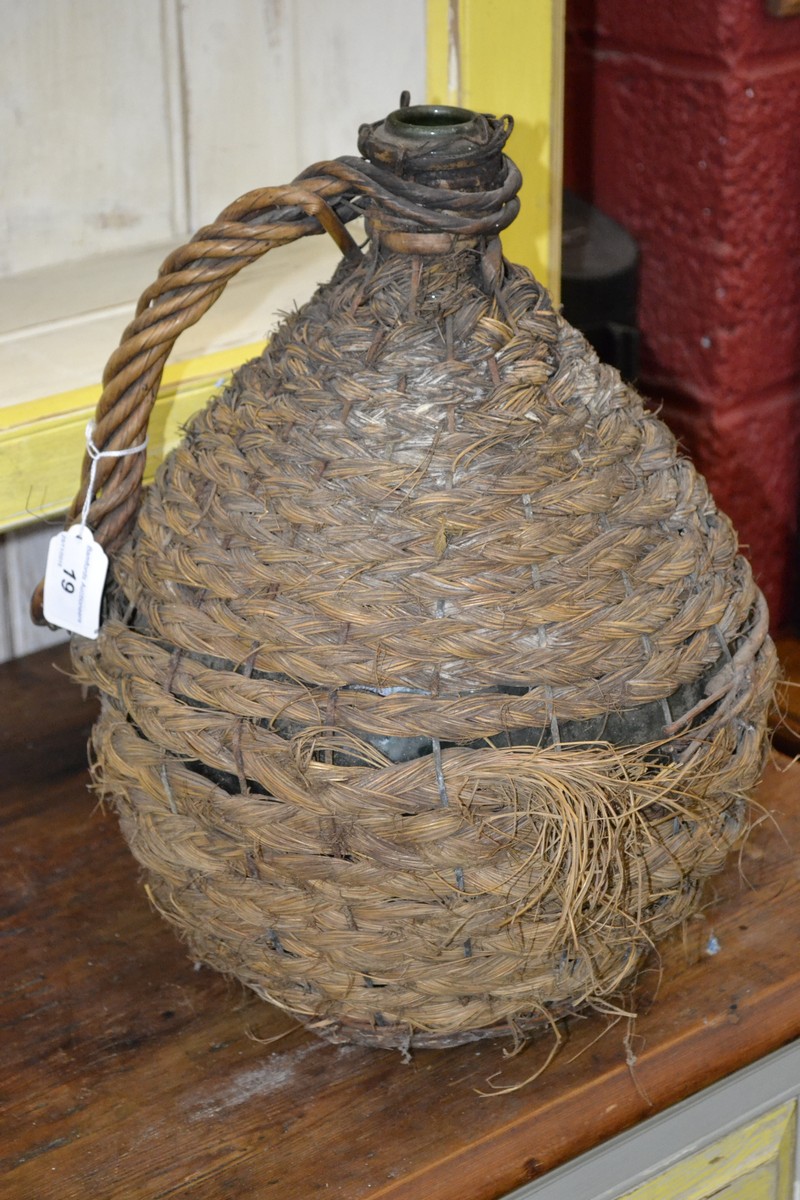 An unusual wicker covered globular bottle, rope twist handle,