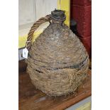 An unusual wicker covered globular bottle, rope twist handle,