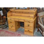 A contemporary pine roll top desk, galleried back, tambour front enclosing pigeonholes,