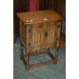 A Priory style oak side cabinet, moulded rectangular top, two carved doors,