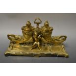 A Victorian brass desk stand, cast with Chinese attendants flanked by cornucopia wells,