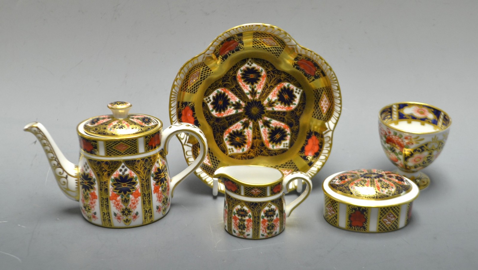 A Royal Crown Derby miniature 1128 Imari tea pot; a milk jug and conforming oval box and cover;