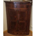 A C19th Georgian mahogany boxwood banded bowfronted corner cabinet with panel doors above three