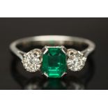 An emerald and diamond three-stone ring: