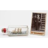 An early 20th century photograph of a sailor, together with a ship in a bottle:,