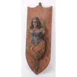 A small figurehead-style carving of a woman:, with curly hair wearing a blue corset,
