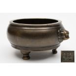 A Chinese bronze tripod censer: of compressed globular form with Buddhist lion-head handles between