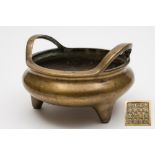 A Chinese bronze tripod censer:  of squat circular form with loop handles to the sides,