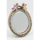 A Meissen porcelain oval dressing table mirror frame: surmounted with two cherubs and decorated