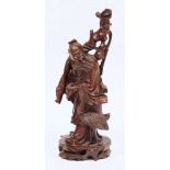 A Chinese carved root wood figure: of a bearded figure in flowing robes holding a bat in his left