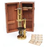 A 19th century brass student microscope in a mahogany case with slides:.