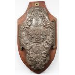 A steel shield-shaped plaque: decorated with neo-classical warriors, grotesque masks and serpents,