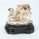 A Japanese carved ivory okimono: in the form of a Samurai warrior pulling a handcart loaded with