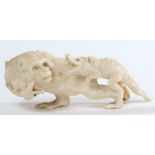 A Japanese carved ivory okimono: of a monkey with mother of pearl eyes holding two young crocodiles,