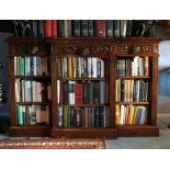 A Victorian oak breakfront bookcase, the top with stiff foliate carved moulded edge, frieze fitted