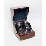 A square mahogany decanter box with decanters and glasses, the brass bound box opening to reveal two