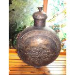 A large Eastern tin vessel of moon flask form, with domed cover and plaited leather strap handle,
