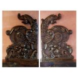 A pair of carved oak panels in medieval style, each with a grotesque beast and a leaf capped strap
