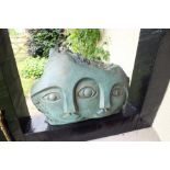 A 20th century bronze effect sculpture in the form of two faces sharing a central eye, broken ragged