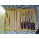 A wooden chopping board and knife rack, containing 6 "Sabatier" knives