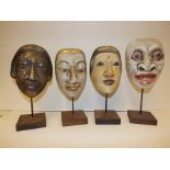 Four various painted Balinese masks with display stands