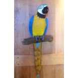 Two 20th century painted carved wood Macaw parrots, on tree branch perches, one 79cm high