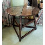 An early 18th century oak cricket table, the circular four plank elm top, three ring moulded