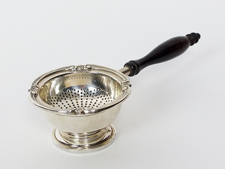 A silver tea strainer and stand, import mark for Garrard & Co. London, the pierced strainer of
