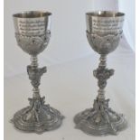 A pair of 20th century ornate pewter goblets, the bowls each engraved with verses from Felix