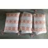 Three cushions, each in pink and cream fabric, with tassels and piped edging