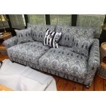 A contemporary deep seated sofa, upholstered in Liberty stylized floral charcoal tones, with scatter