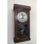 An Edwardian mahogany cased wall clock, having circular silvered dial with Arabic numerals, bevel