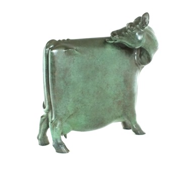 A bronze figure of a cow standing four square, it's head turned licking its back, green