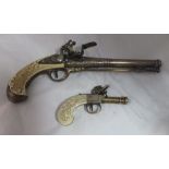 Two reproduction flintlock design pistols, yellow metal finish, with ivory effect handles, largest