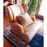 A pair of contemporary wingback easy chairs upholstered in two tone caramel leather, raised on