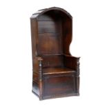 A late 18th century provincial oak hall porter's chair, the arched hood over a panelled back with