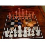 An Indian stained red and white ivory chess set, intricately turned, leaf carved and pierced