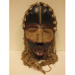 A West African Dan mask with cowrie shells and painted details